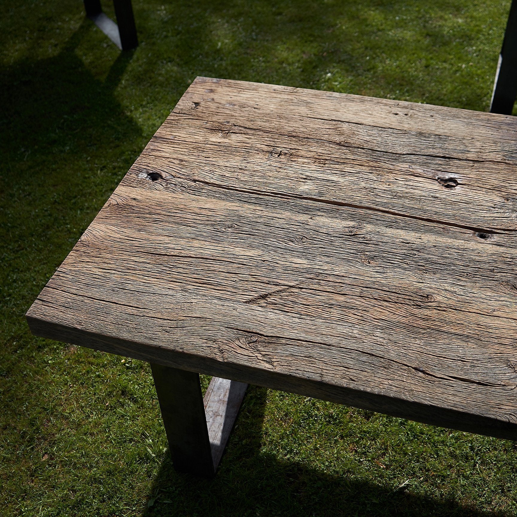 Tisch aus Altholz Eiche und originaler und gebürsteter Oberfläche auf Rohstahlframes im Gras